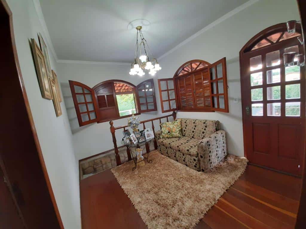 Sala de estar da Casa da Tuca com sofá do lado direito da imagem e em frente ao sofá uma mesa de vidro.