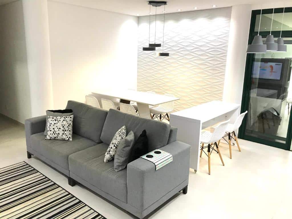Sala de estar do Apartamento Resort em Praia grande - Ubatuba com sofá de dois lugares a frente no centro do ambiente ao fundo duas mesas com cadeiras. Representa airbnb na praia do Tenório.