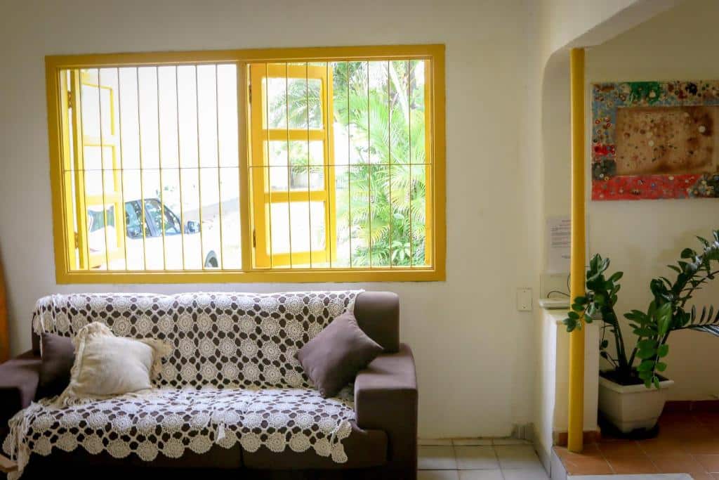 Sala de estar do Pé na Areia – Casa para temporada com sofá do lado esquerdo da imagem e ao fundo uma janela ampla.