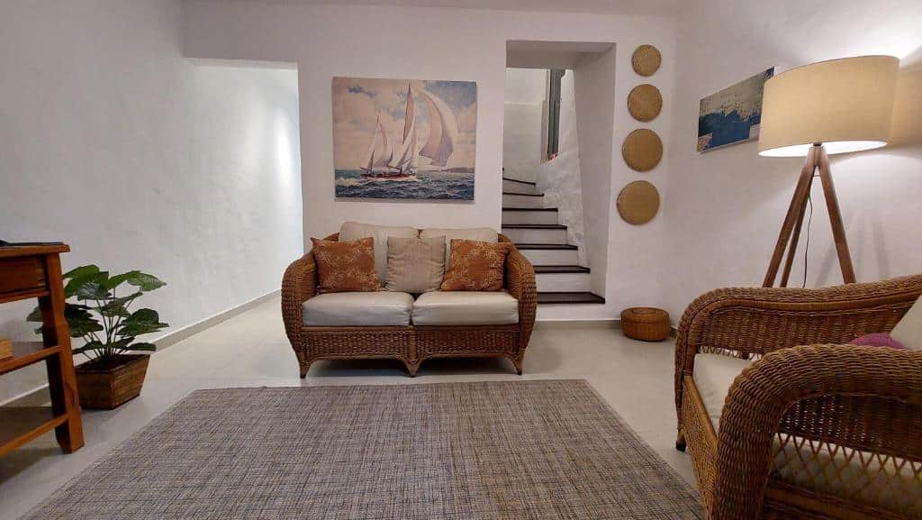 Sala de estar do Maré Mansa Barê com uma poltrona do lado direito da imagem e do lado direito da poltrona um sofá.