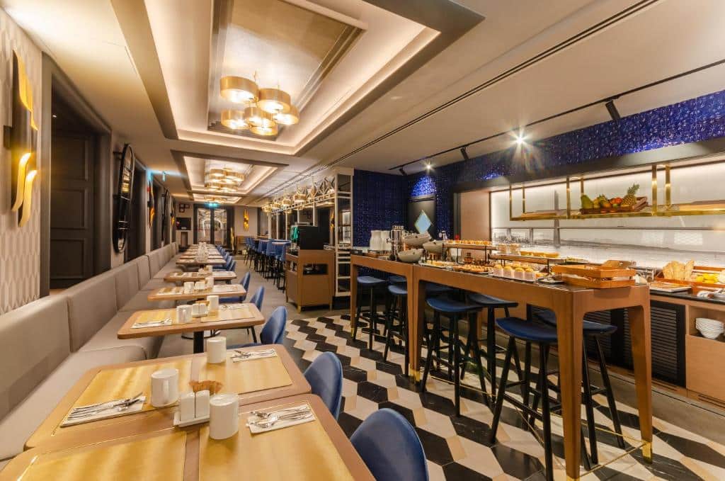 Área de refeições do Eurostars Lisboa Baixa decorada em tons de bege e azul, no espaço há bancadas e mesas com itens de café da manhã, e pequenos sofás estofadas junto de mesas e cadeiras