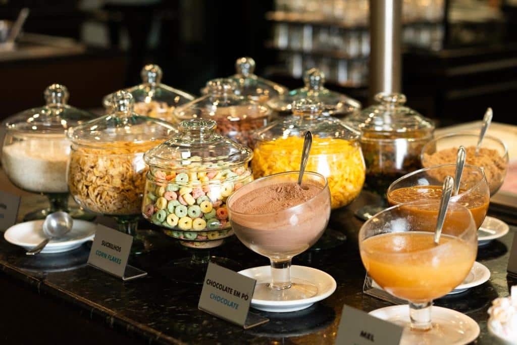 Foto do San Rafael Comfort Class Hotel, mostrando uma bancada com vários potes de vidro contendo diferentes alimentos para o café da manhã no hotel.
