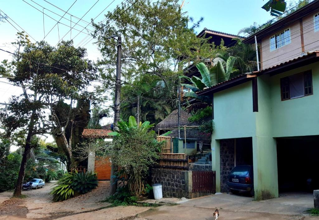 Vista de fora da Suíte Som do Mar da Vermelha do Centro. É possível ver uma propriedade de dois andares, com espaço para garagem. Existem várias árvores em volta.