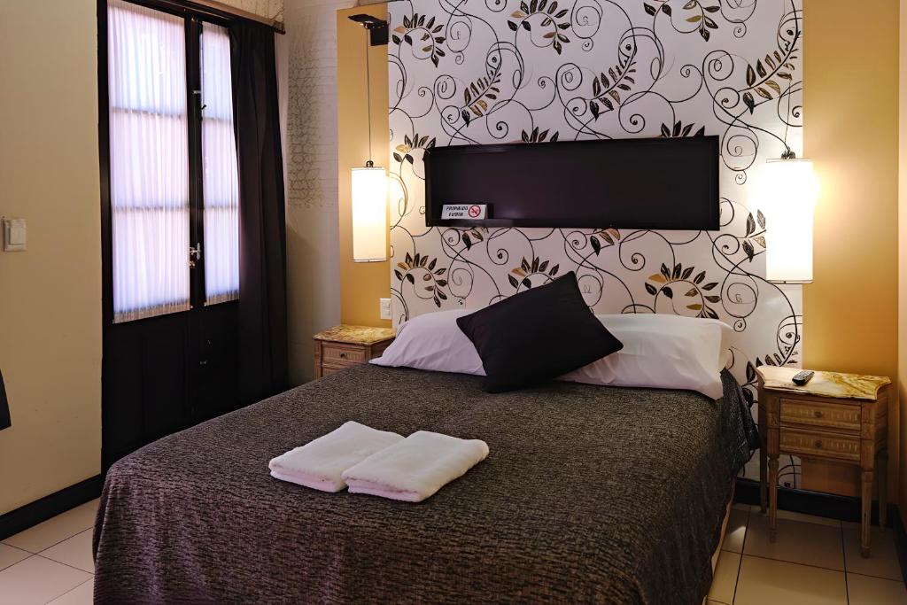 quarto da Pasaje Solar, um aluguel de temporada em Buenos Aires, com cama de casal, luminária e mesinha em ambos os lados, nicho de parede e uma janela grande de madeira 