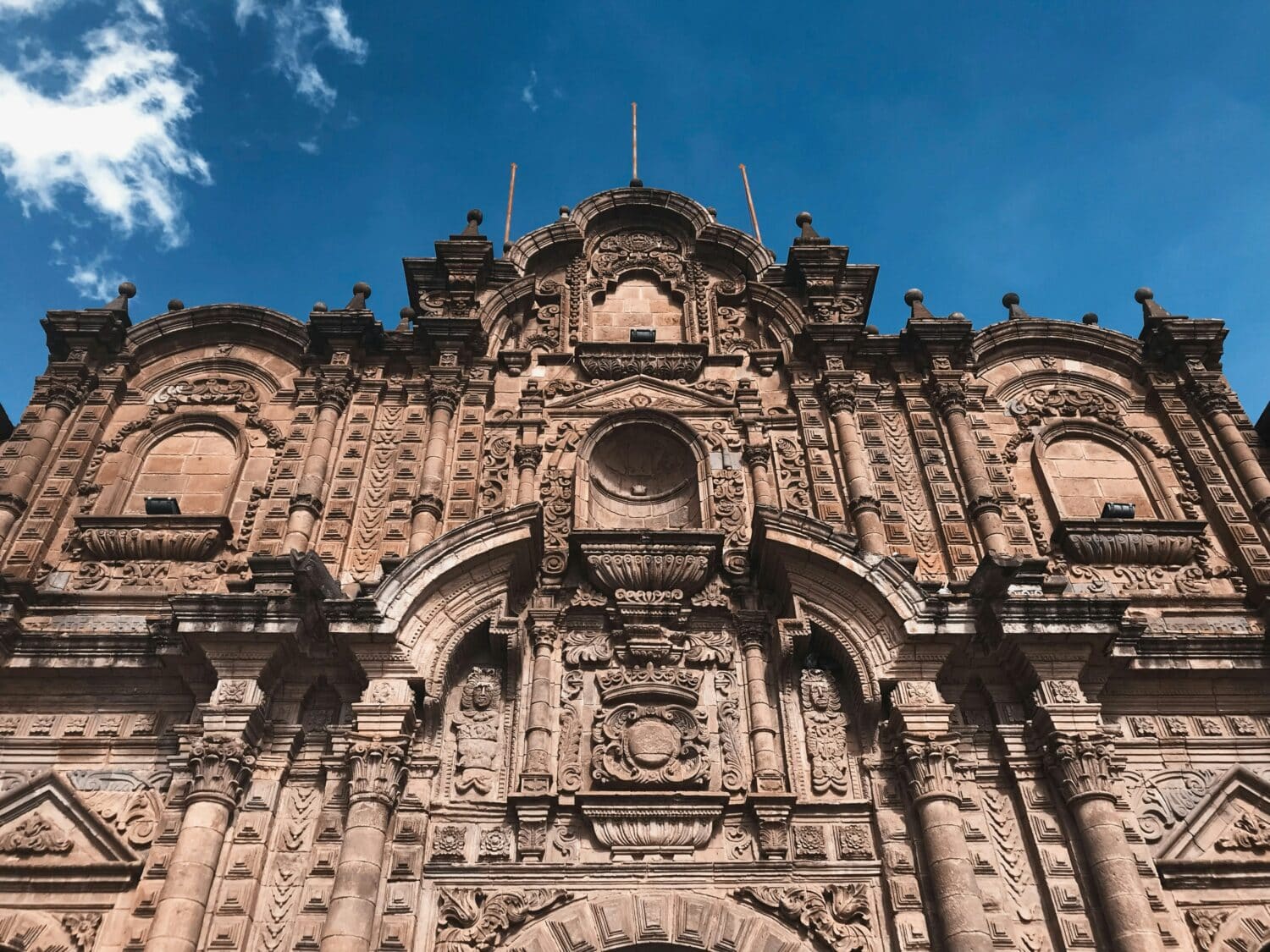 Vista frontal da Catedral Basílica da Virgem da Assunção em Cusco mostrando a entrada de pedra da igreja com uma bela arquitetura.