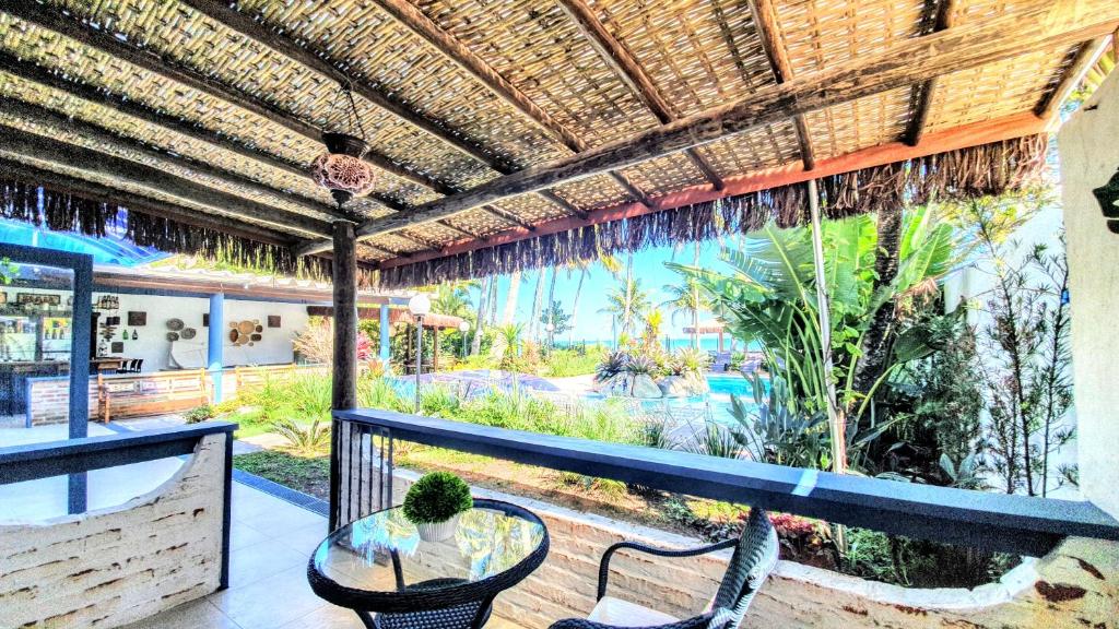 Imagem da varanda do Brisa do Mar Barê Praia Hotel com uma cadeira e uma mesa redonda e em frente o jardim.