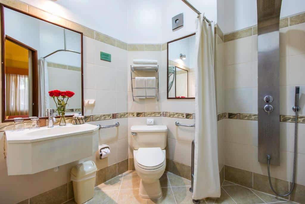 banheiro adaptado para cadeirantes no Xima Exclusive Cusco com box de chuveiro amplo, barras de apoio perto do vaso sanitário e pia vazada com acesso para cadeira de rodas.