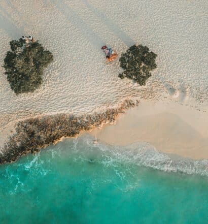 Imagem de cima dapraia em Aruba durante o dia com mar abaixo e em cima faixa de areia. Representa o que fazer em Aruba.