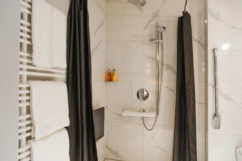 Banheiro com acessibilidade do Boutique Hotel Glacier com chuveiro do lado esquerdo e do lado direito uma barra de apoio..