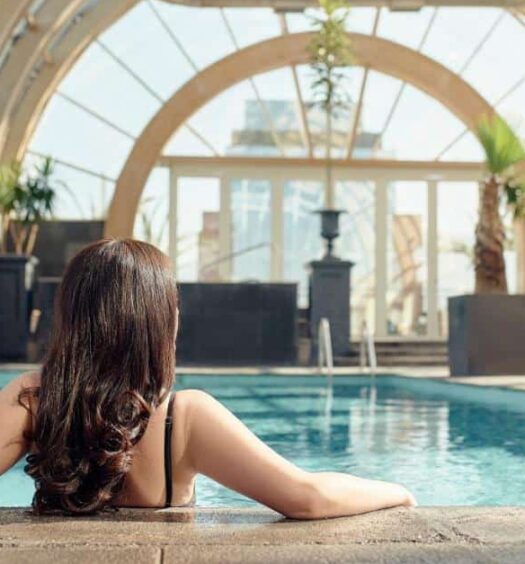 Imagem de uma mulher no centro dentro da piscina coberta do The Ritz-Carlton, Santiago. Representa hotéis com piscina em Santiago