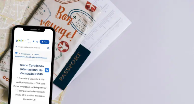 Um passaporte, alguns documentos e um celular com o site do Governo Brasileiro aberto na parte de certificações em cima de uma mesa branca, para representar Certificado Internacional de Febre Amarela