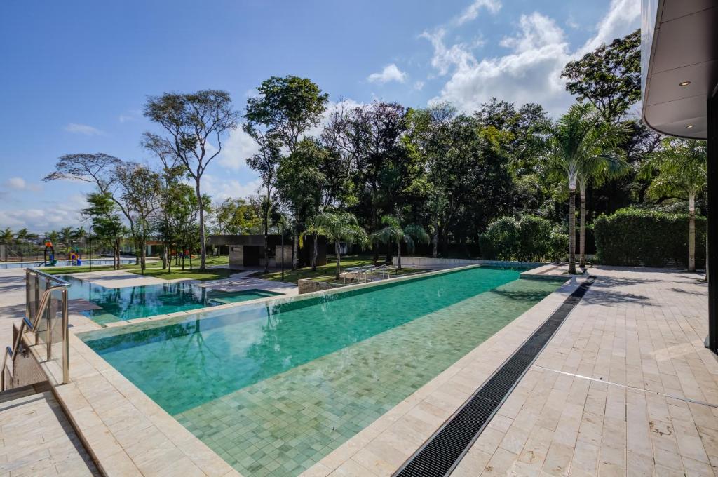 Parte do DoubleTree by Hilton que mostra uma grande piscina ao ar livre moderna com várias árvores em volta durante o dia. Imagem ilustrando post Resorts em Foz do Iguaçu.