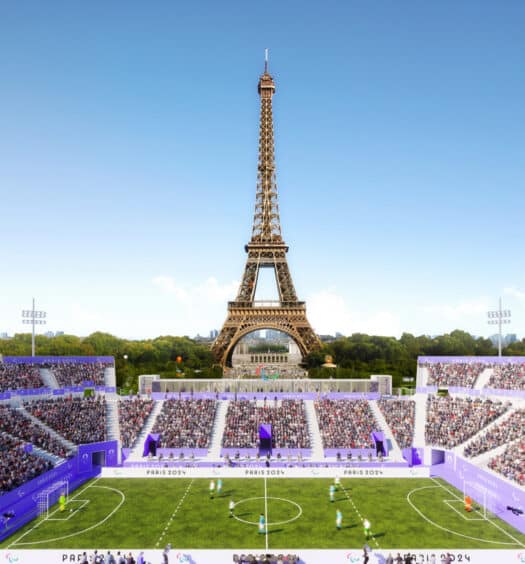 Estádio repleto de pessoas assistindo a um jogo de futebol com a Torre Eiffel logo atrás para ilustrar o post sobre onde ficar em Paris nas Olimpíadas de 2024.