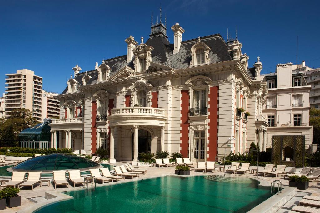 fachada imponente parecendo um castelo ou mansão do hotel cinco estrelas Four Seasons Hotel Buenos Aires com piscina e espreguiçadeiras ao redor
