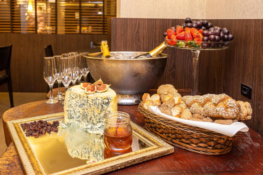 Uma foto mostrando uma mesa com queijos, taças, frutas, pães e balde com champagne em Faial Prime Suítes.