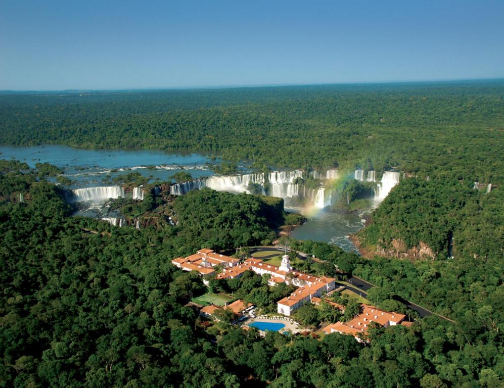 Visão aérea do Parque Nacional, do Hotel Belmond e das Cataratas de Foz do Iguaçu. Um arco-íris está sobre as cataratas.