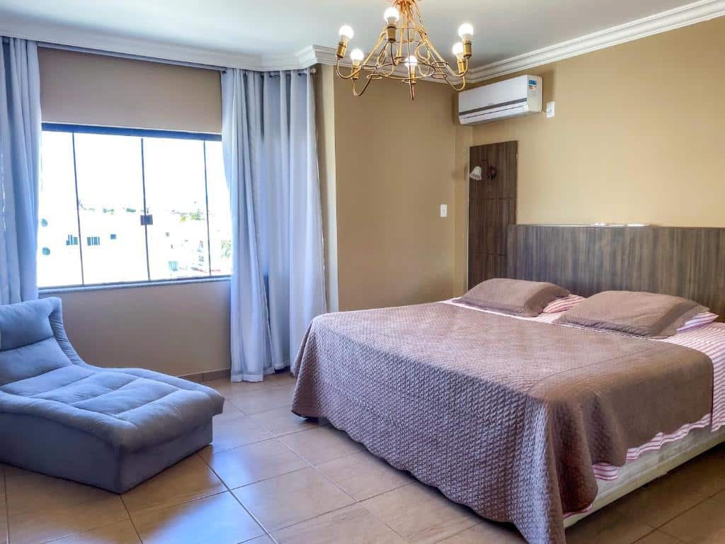 Quarto do Hotel & Pousada Sonho Meu. Uma cama de casal do lado direito e um ar-condicionado, do lado esquerdo uma poltrona e atrás a janela. Foto para ilustrar post sobre pousadas pet friedly em Santa Catarina.