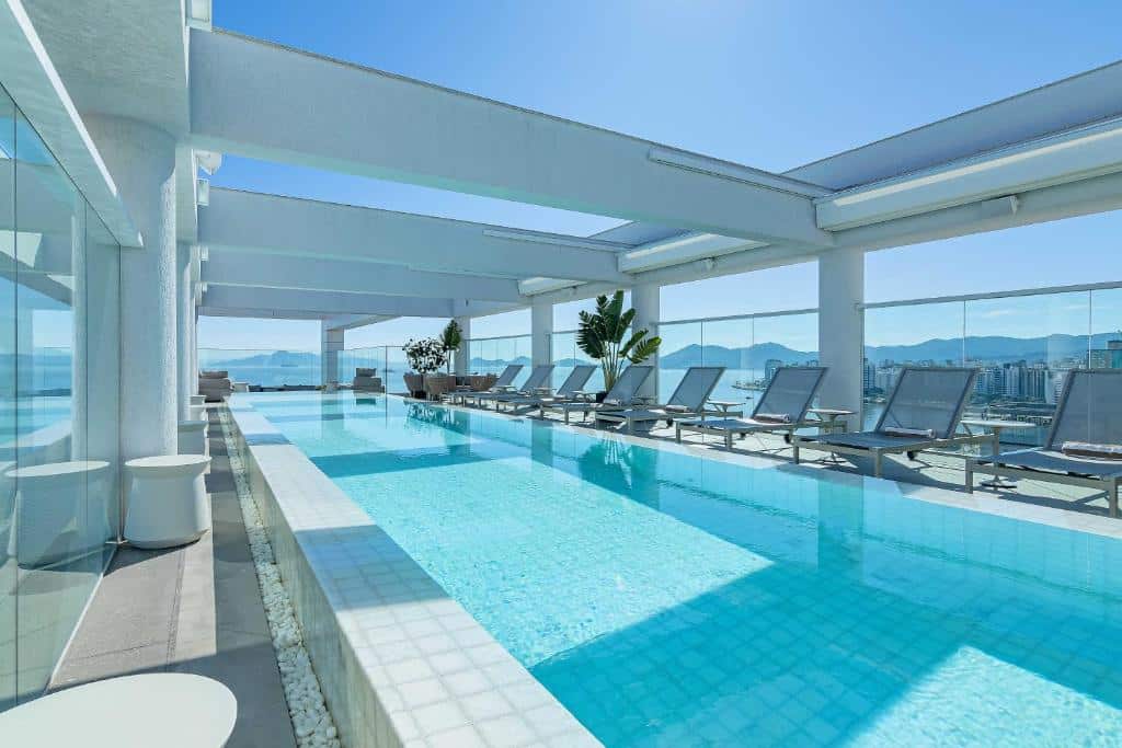 LK Design Hotel Florianópolis, uma imagem que mostra sua piscina no terraço. Possui espreguiçadeiras no deck e tem vista para a cidade.