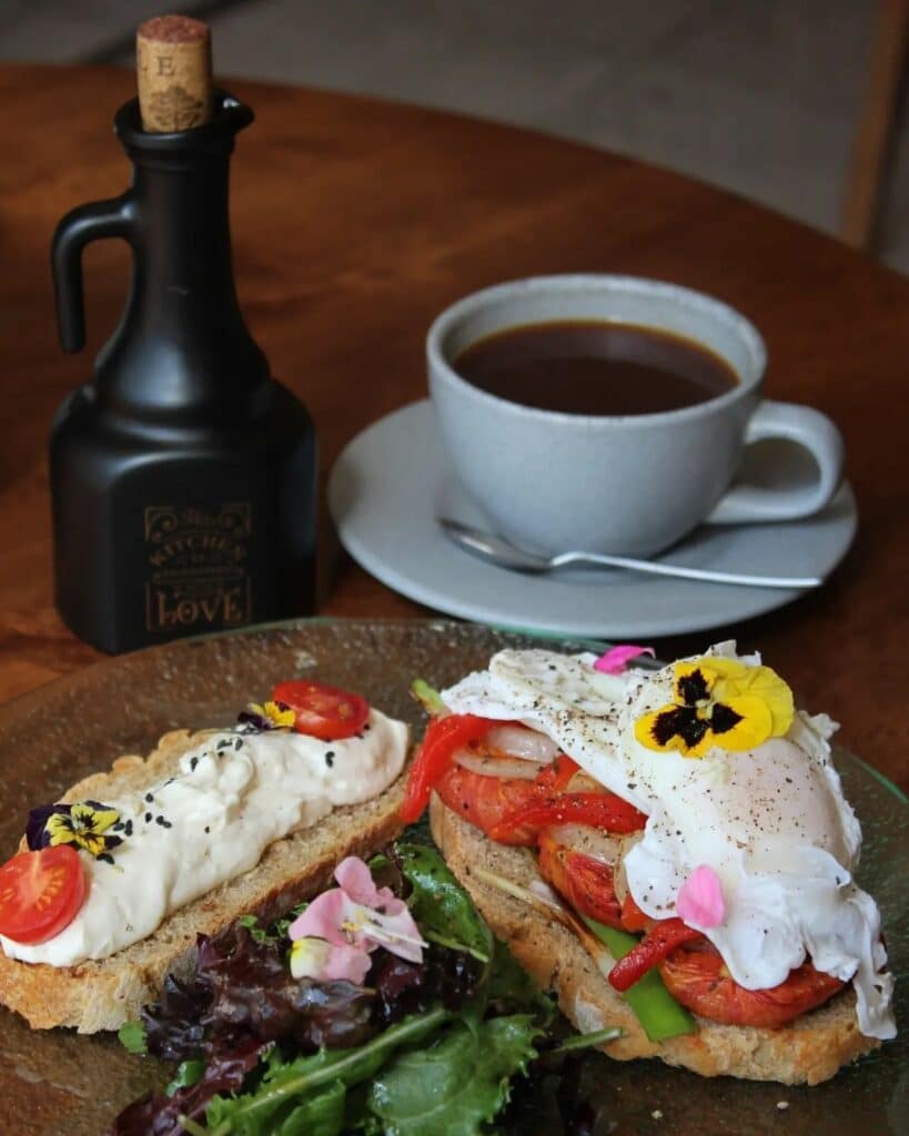 prato de pães torrados com tomates, saladas e patês, acompanhado de uma xícara de café no Organika Bakery & Coffee