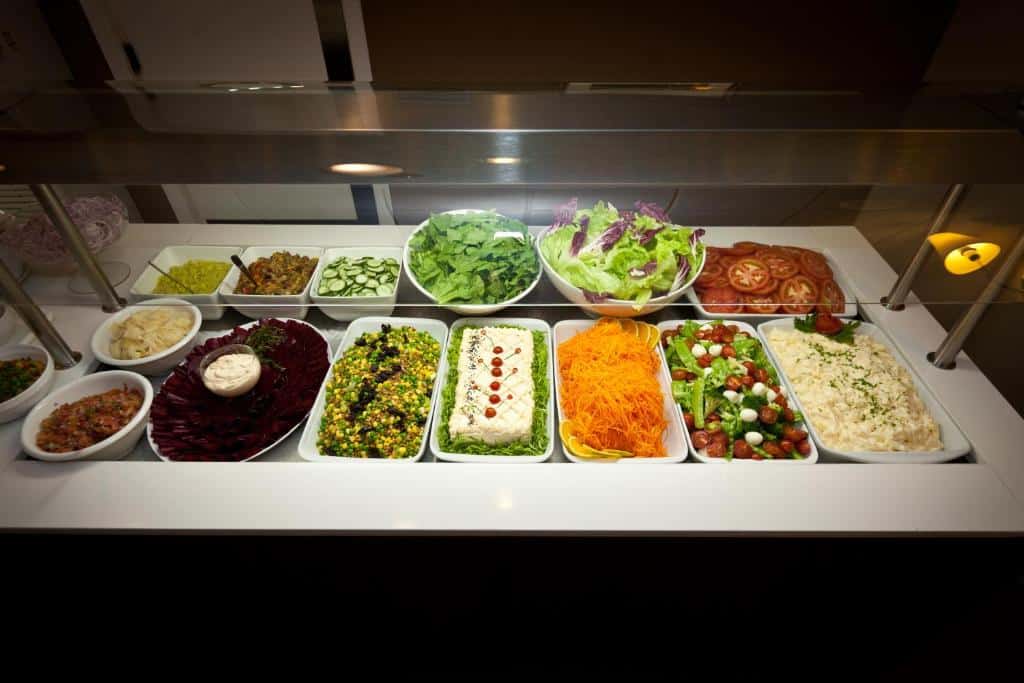 Porto da Ilha Hotel, uma imagem que mostra um buffet do hotel. Há opções de verduras, legumes, saladas, molhos, etc.