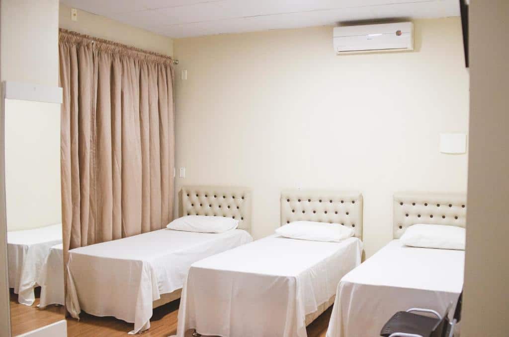Quarto da Pousada Center. Três camas de solteiro, em cima um ar-condicionado. Foto para ilustrar post sobre pousadas pet friedly em Santa Catarina.