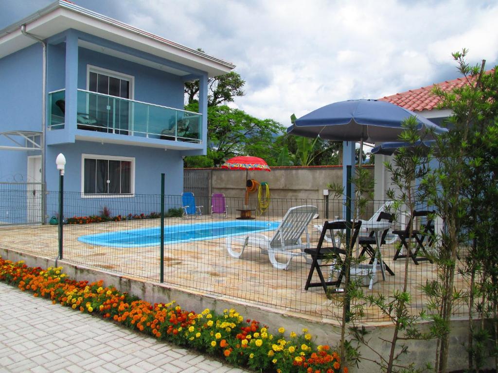 Área externa da Pousada Guanumbi. Uma piscina no centro, do lado direito guarda-sol e cadeiras, do lado esquerdo a pousada. Foto para ilustrar post sobre pousadas pet friendly no Paraná.