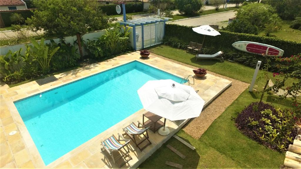 Vista de cima da área externa da Pousada Manaaki. Uma piscina no meio, ao redor guarda-sóis, jardim e cadeiras de descanso.