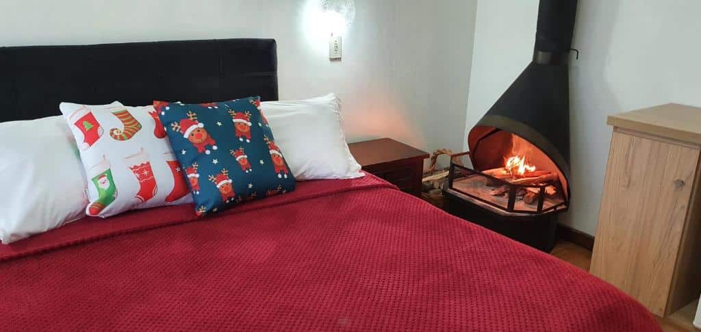 Quarto da Pousada Natal Encantado. Uma cama de casal, do lado direito uma lareira. Foto para ilustrar post sobre pousadas pet friendly em Gramado.