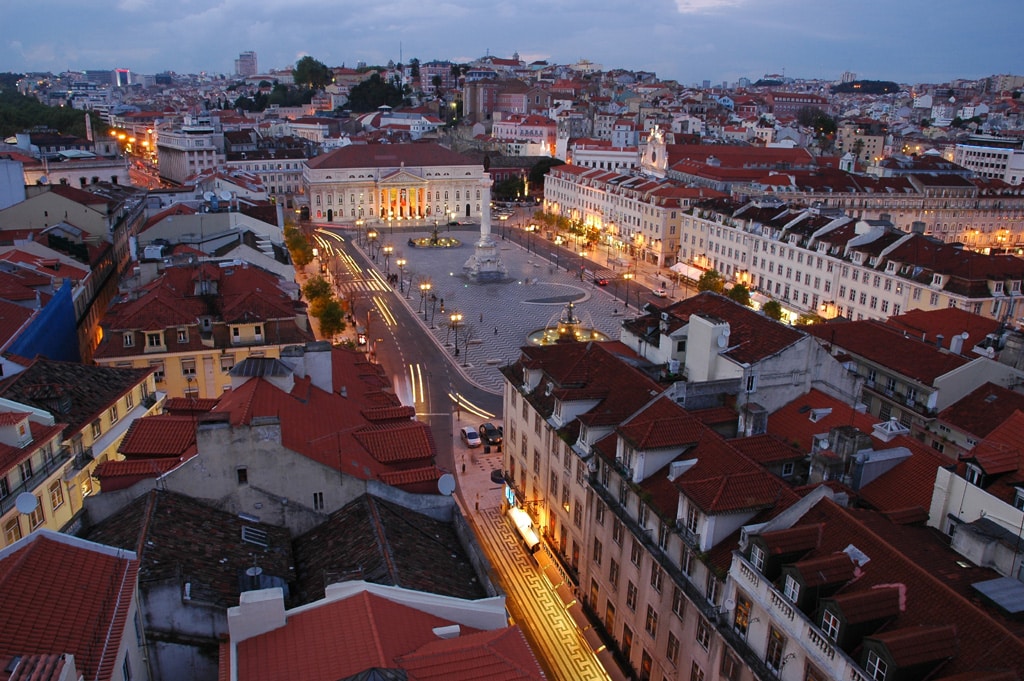 Praça do Rossio em Lisboa, trata-se de um espaço ao ar livre com duas fontes em suas extremidades, no meio há uma monumento, e nos arredores da praça há construções de época