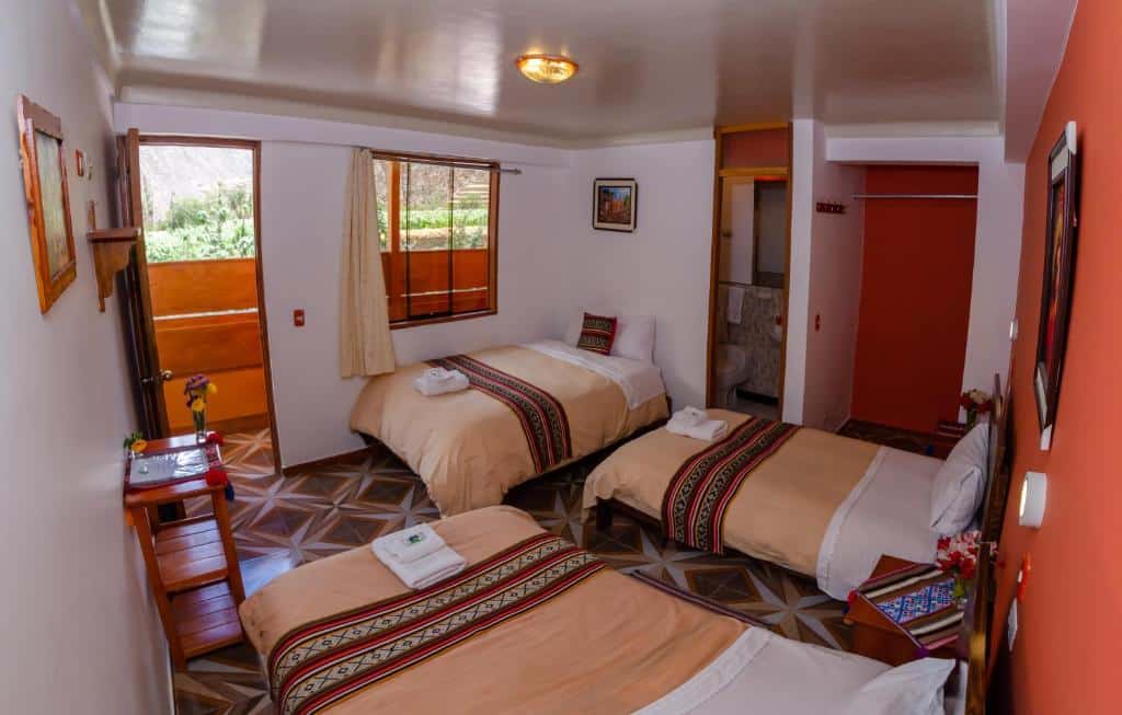 Quarto familiar do Peru Quechua's Lodge Ollantaytambo no Vale Sagrado dos Incas com três camas de solteiro dispostas ao longo do espaço, ocupando todo o ambiente. No canto, ao centro, há uma pequena porta que dá acesso ao banheiro da suíte, para representar hotéis no Vale Sagrado dos Incas.