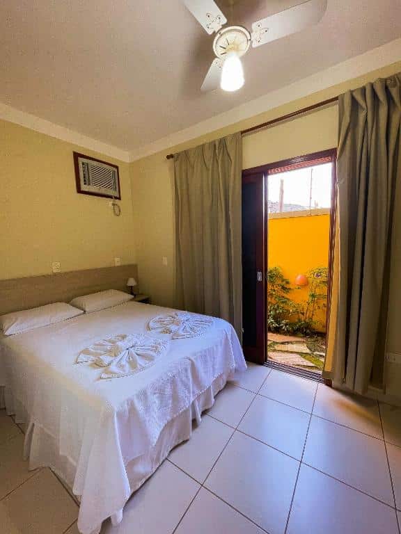 Foto do quarto em Recanto das Tiribas. Ilustra o post sobre Onde ficar em Ilhabela. Há uma cama de casal na esquerda, e do seu lado há uma porta com passagem para o quintal.