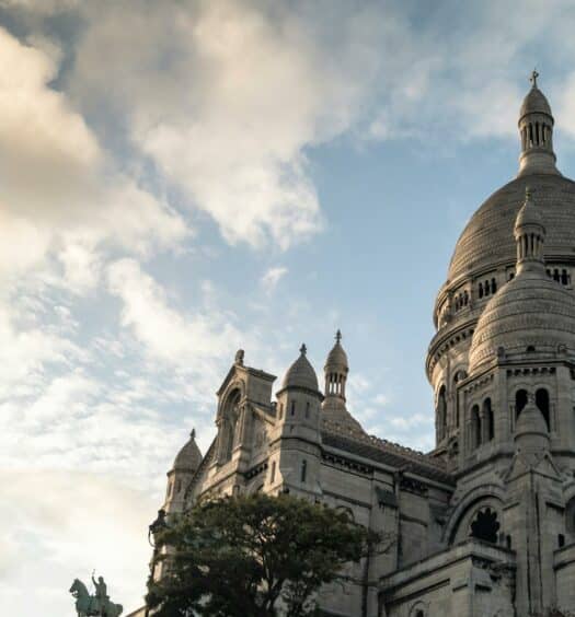 Basílica de Sacré-Coeur vista de baixo com o céu azul ao lado. A imagem ilustra o post sobre hotéis em MontMartre. - Foto: Juan Martin Lopez via Pexels