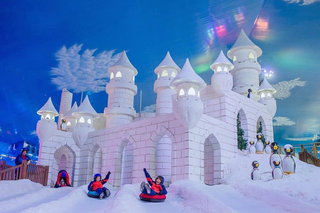 vista de um castelo de gelo na Snowland, com crianças escorregando em boias redondas e bonecos de neve ao redor