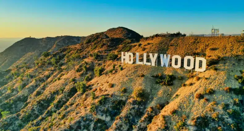Imagem, no final do dia , do letreiro de Hollywood do lado direito da imagem no meio das montanhas. Representa Los Angeles.