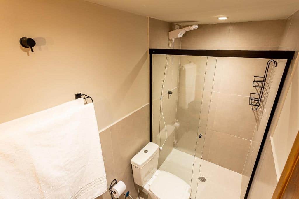 Vista de cima do banheiro da Casa Savana. Uma toalha e um vaso sanitário do lado esquerdo, no fundo o box.