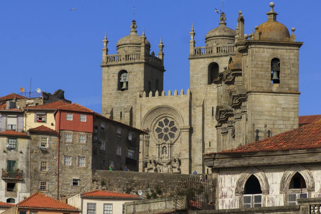 Imagem da Catedral da Sé do Porto durante o dia com casinhas a frente e ao fundo a catedral.
