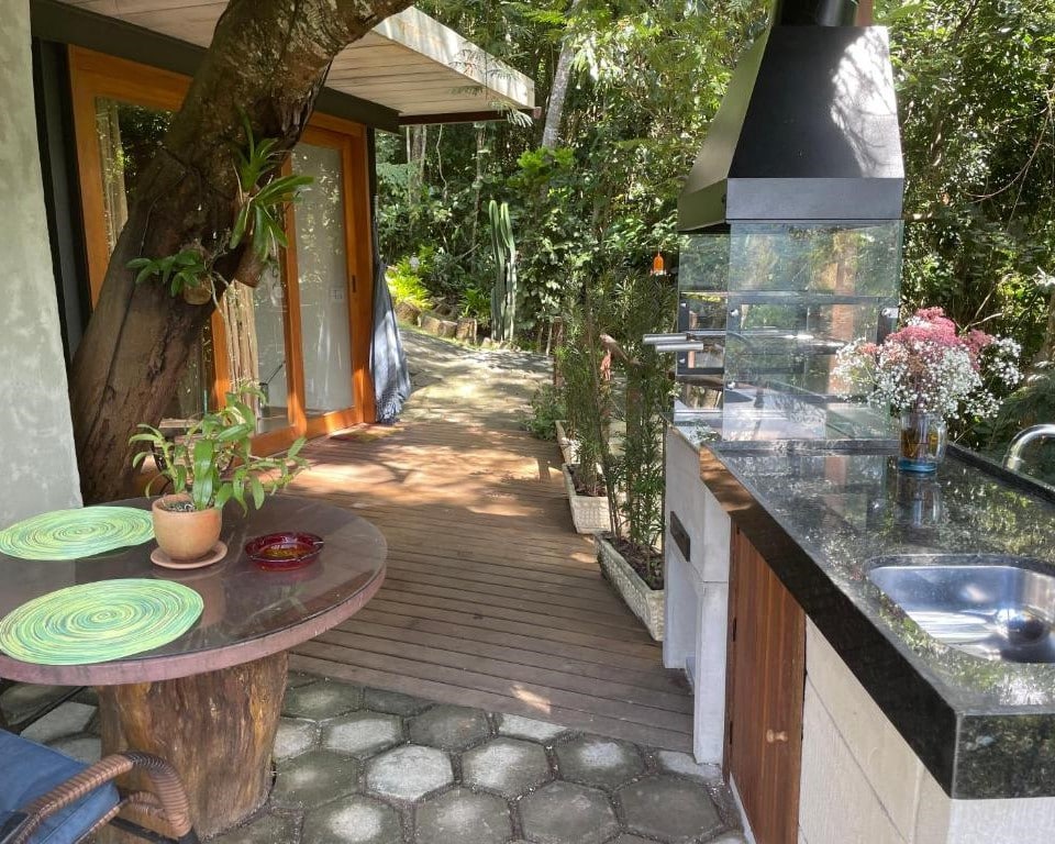 Lado de fora do Chalé mais bucólico de Araras com uma cozinha externa. Há uma churrasqueira, pia e mesa. A foto está na lista de chalés em Petrópolis.