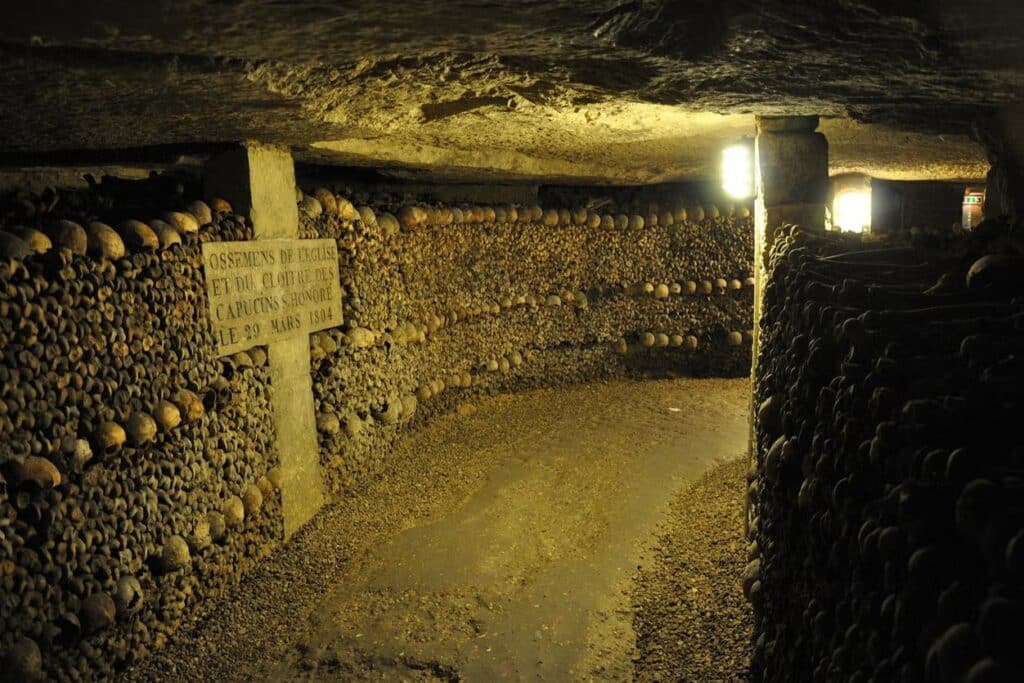 Corredor subterrâneo com paredes de ossos e crânios nas Catacumbas, uma das opções de o que fazer em Paris.