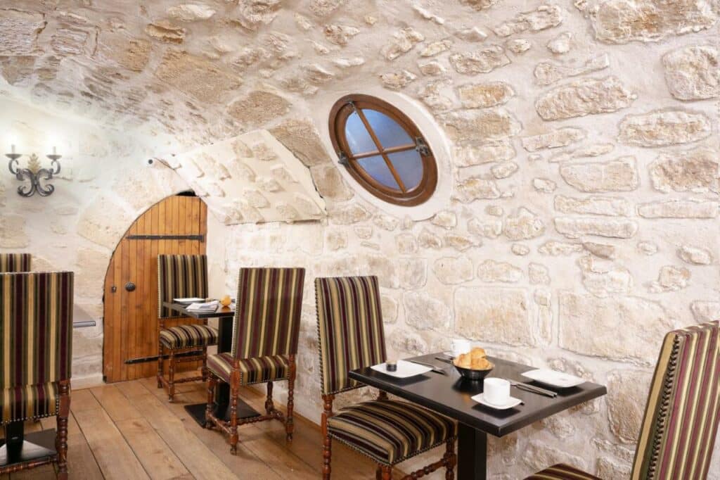 Sala de refeições do Hotel Saint-Louis Marais, onde algumas mesas com cadeiras estão dispostas.