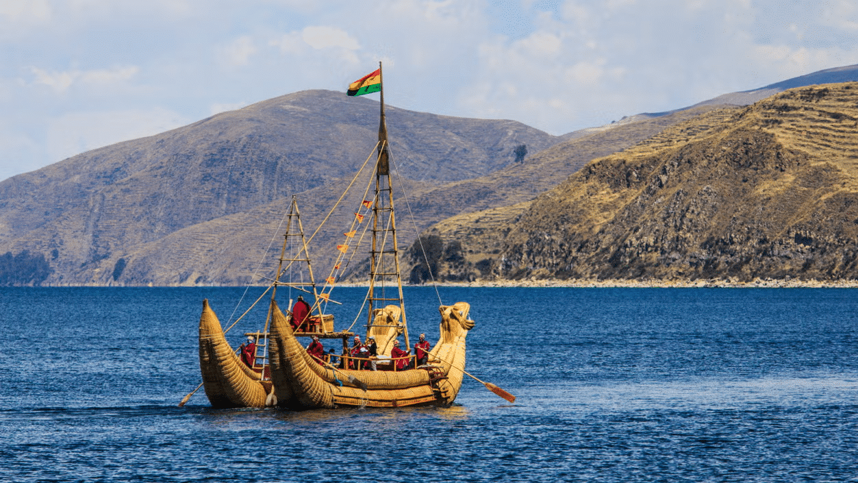 Barco típico do Peru no Lago Titicaca, com montanhas ao fundo, durante um dia ensolarado. Representa o que fazer no Peru