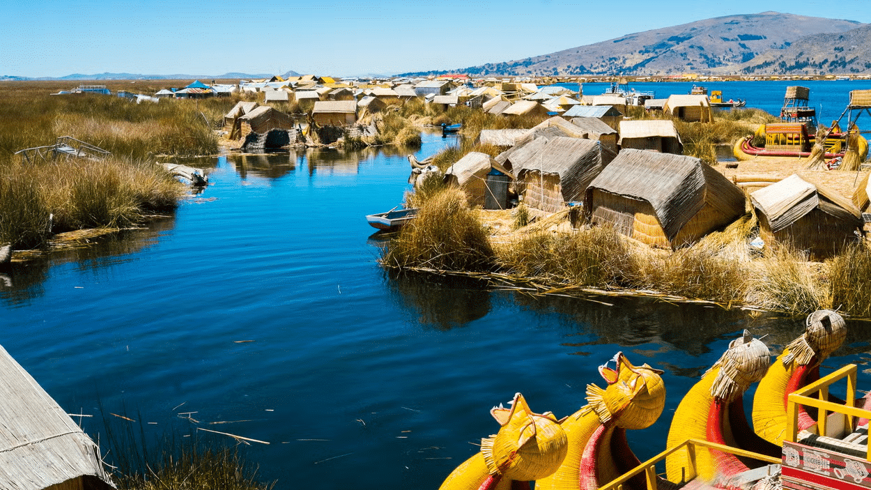 Povoado, localizado em meio ao Lago Titicaca, com ilhas no meio do lago rodeada de natureza e casinhas com teto de palha.