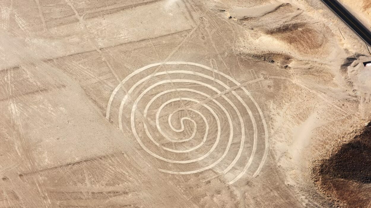 Vista aérea de um campo extenso de areia, com um desenho histórico de um espiral no chão. Representa o que fazer no Peru. Foto: Civitatis