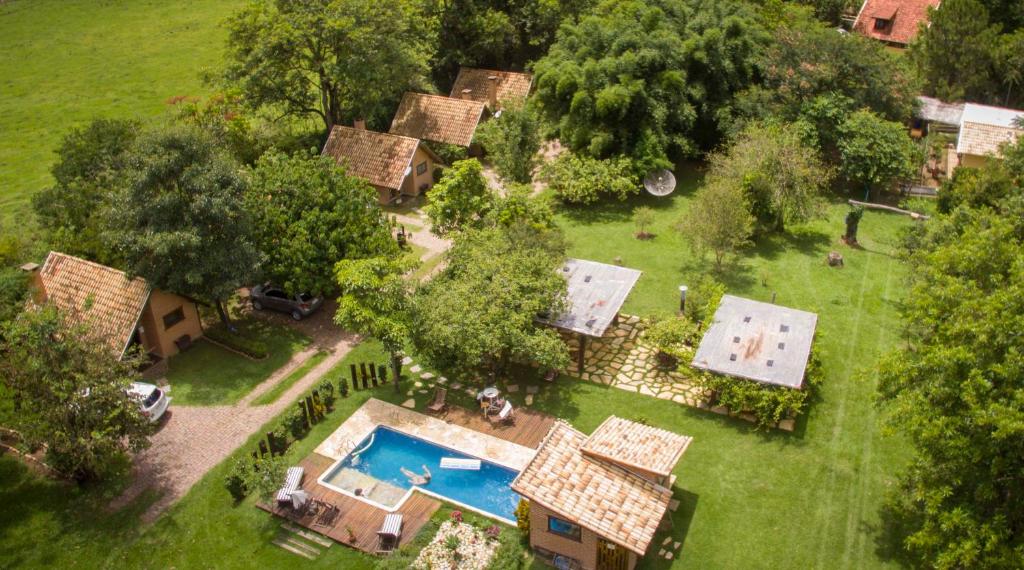 Vista de cima da Pousada Canto da Lua. Do lado esquerdo chalés, entre eles árvores. No meio uma piscina.