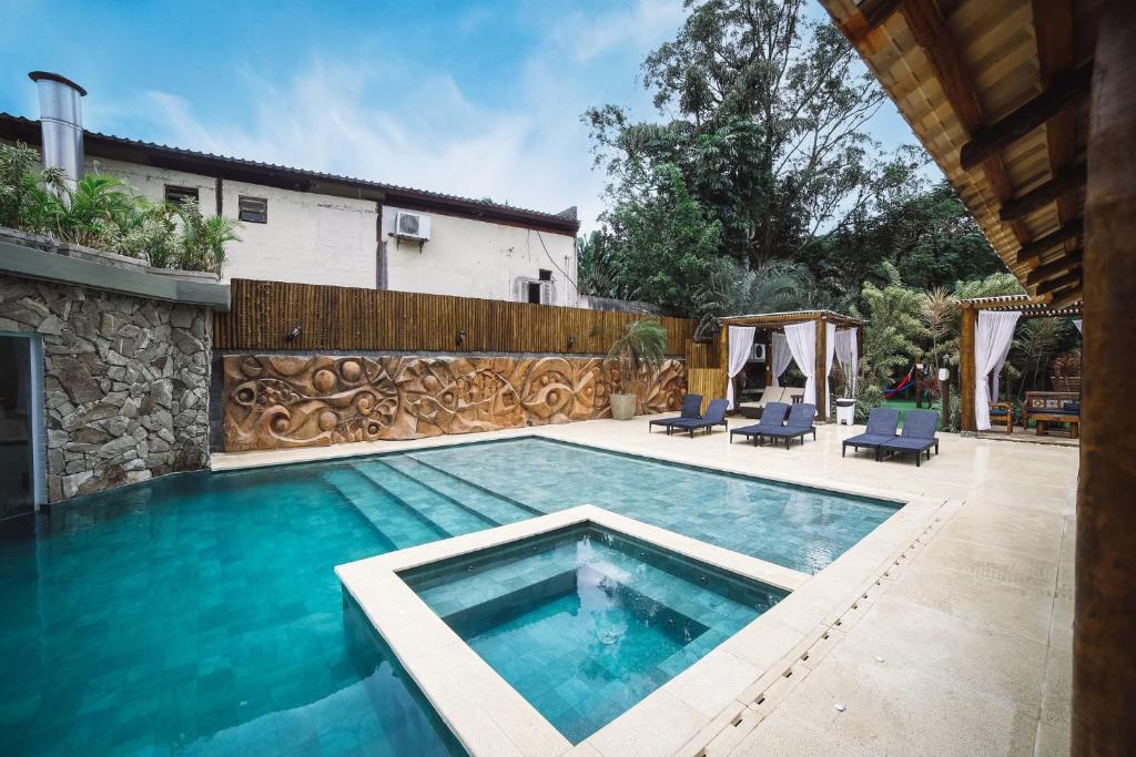 Área externa da Pousada Porto Mare. Uma piscina com hidro, no fundo, do lado direito, cadeiras de tomar sol e pergolado.