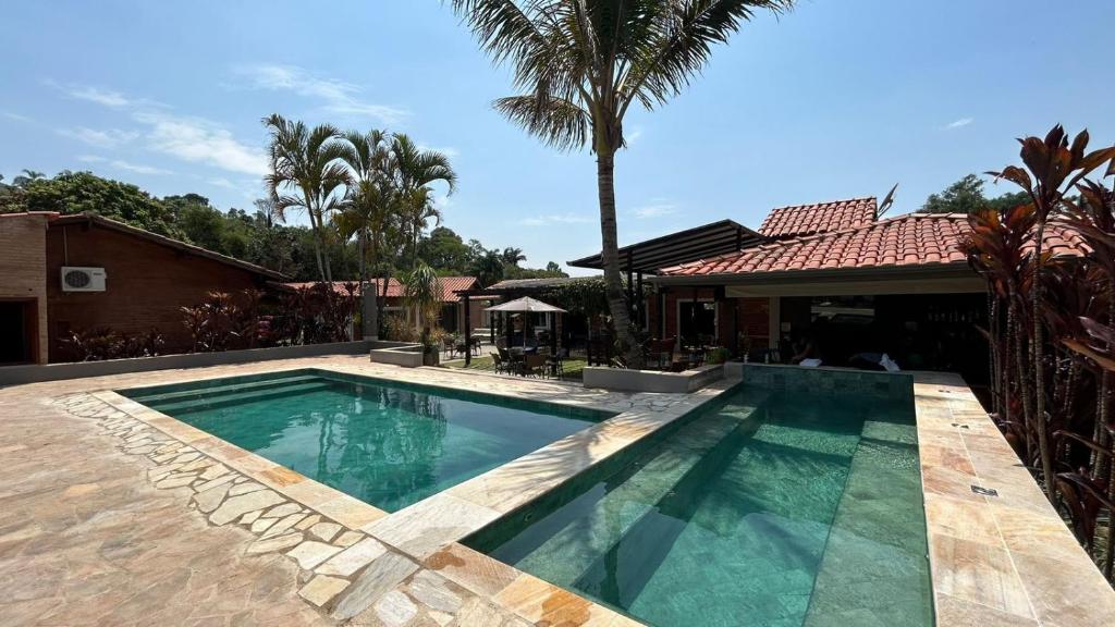 Duas piscinas ao ar livre da Pousada Vale das Orquídeas. No fundo o bar.