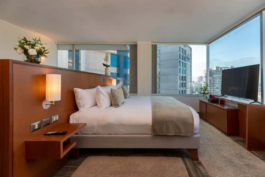 Quarto do Best Western Premier Marina Las Condes com cama de casal do lado esquerdo da imagem e em frente a cama uma cômoda com TV. Representa hotéis no Bairro Las Condes em Santiago.