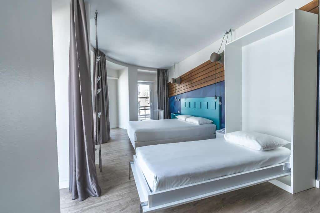 Quarto do Ibis Styles Lisboa Centro Liberdade NE com uma cama de casal, uma de solteiro, duas sacadas e uma televisão, para representar hotéis 3 estrelas em Lisboa