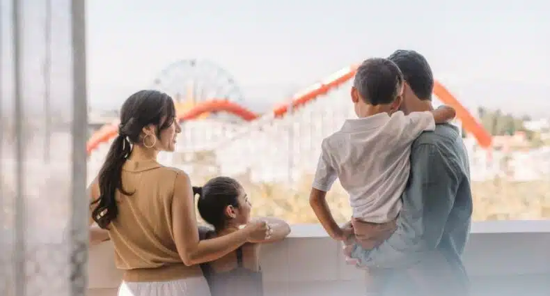 Varanda do quarto do The Westin Anaheim Resort com dois adultos e duas crianças olhando para a montanha do parque. Imagem para ilustrar post sobre hotéis perto da Disney Califórnia.