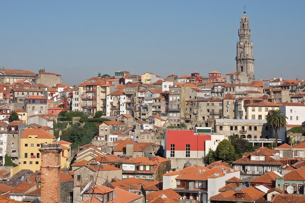 Imagem da cidade do Porto a frente durante o dia com várias casas a frente e do lado direito ao fundo a Torre dos Clérigos.