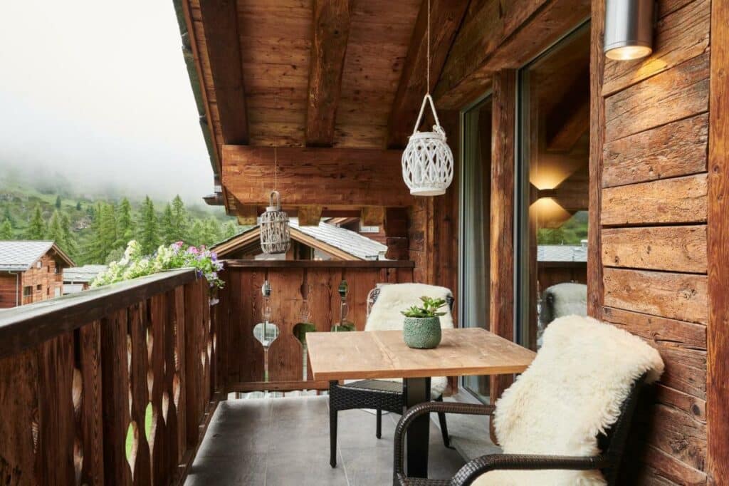 Varanda do Matthiol Boutique Hotel durante o dia com uma mesa e duas cadeiras com lado direito da imagem com vista para as montanhas.